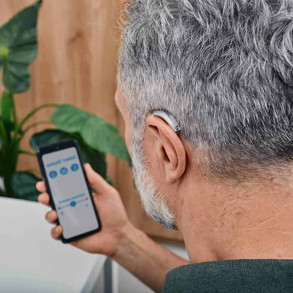 man adjusting hearing aid levels on app