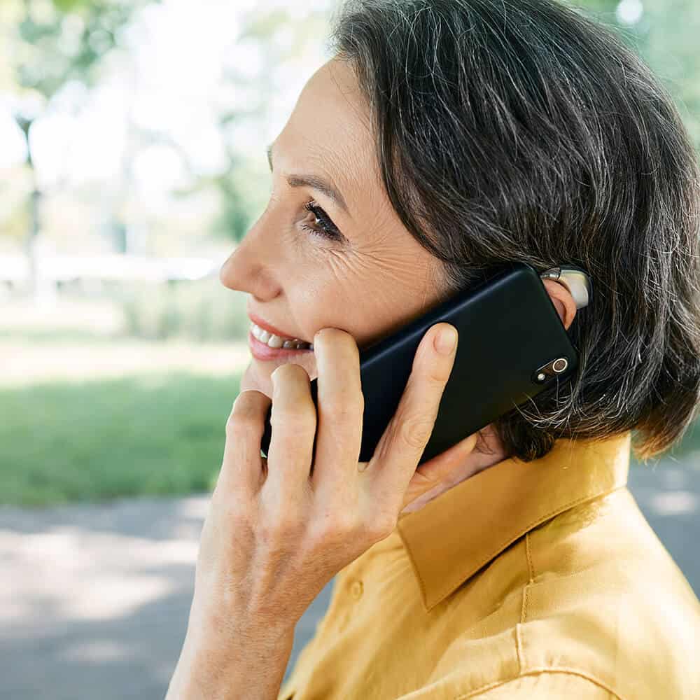 woman with hearing aid on phone